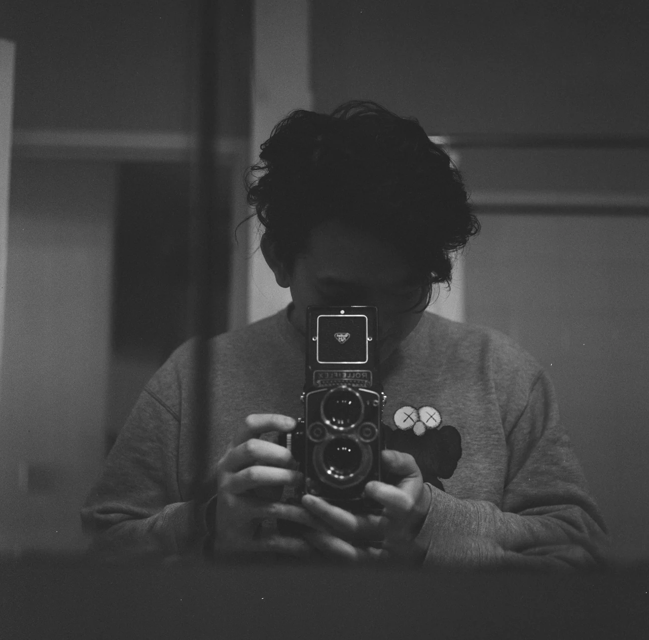 Black-and-white portrait of Tian holding a twin-lens camera