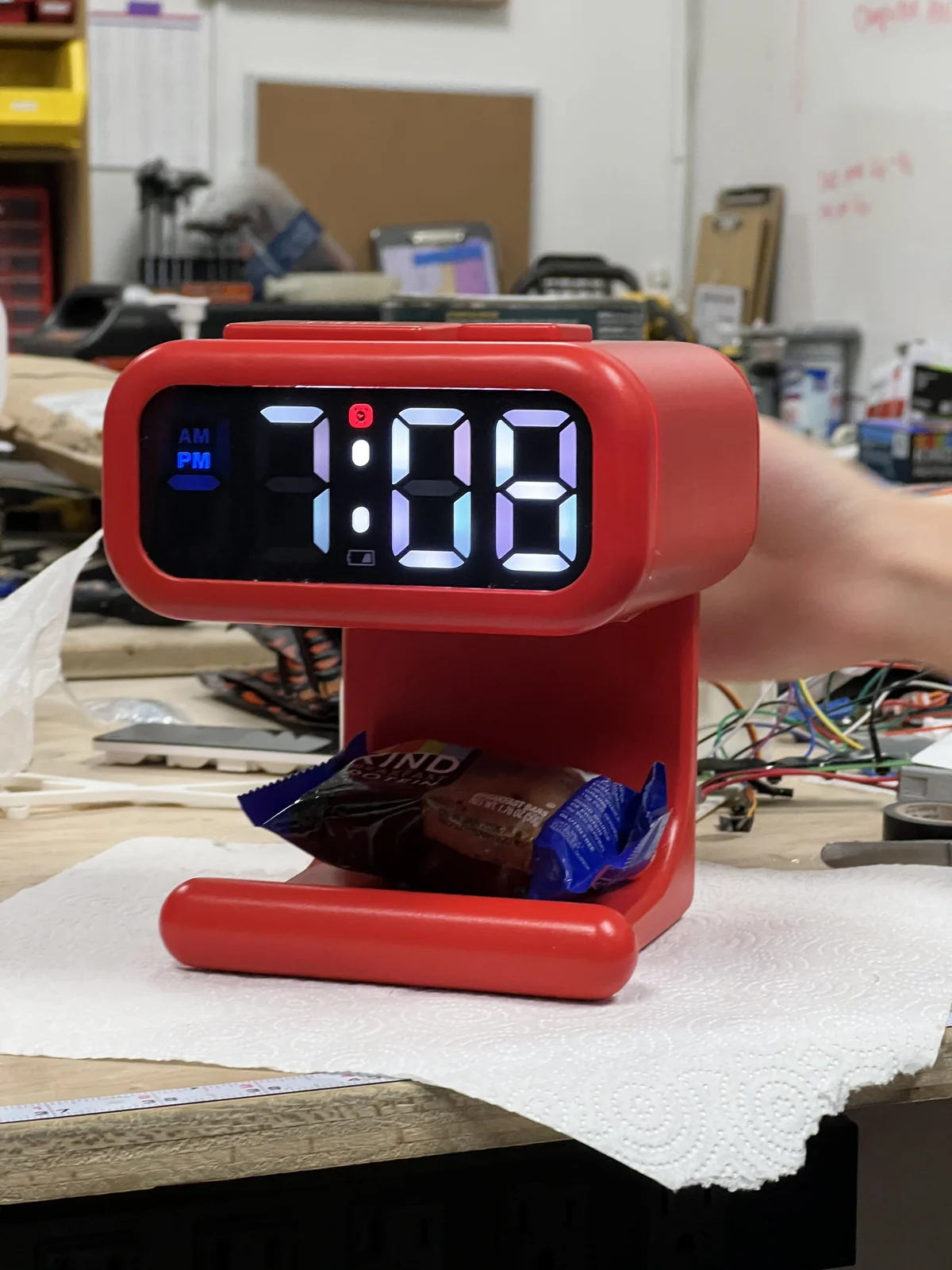 A red clock with its illuminated digital display and a KIND bar beneath it
