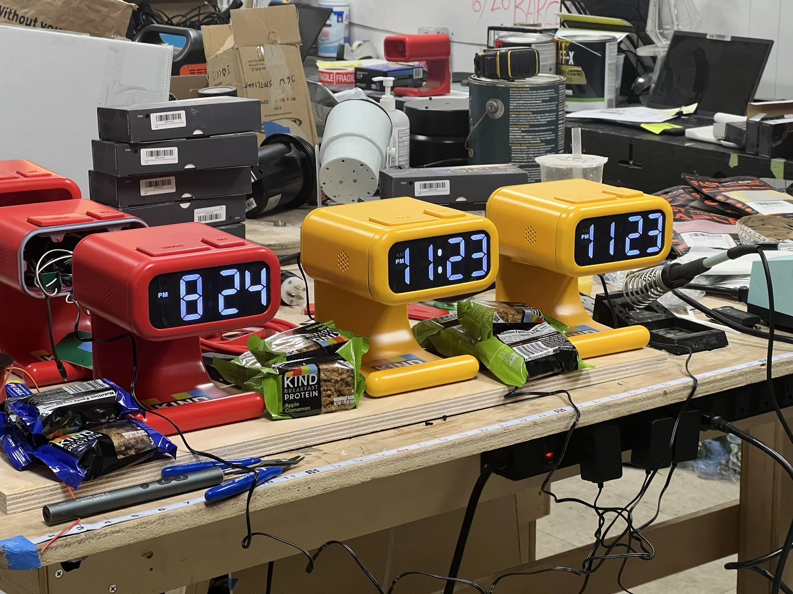 Red and yellow KIND Bar Alarm clocks lined up on a workbench