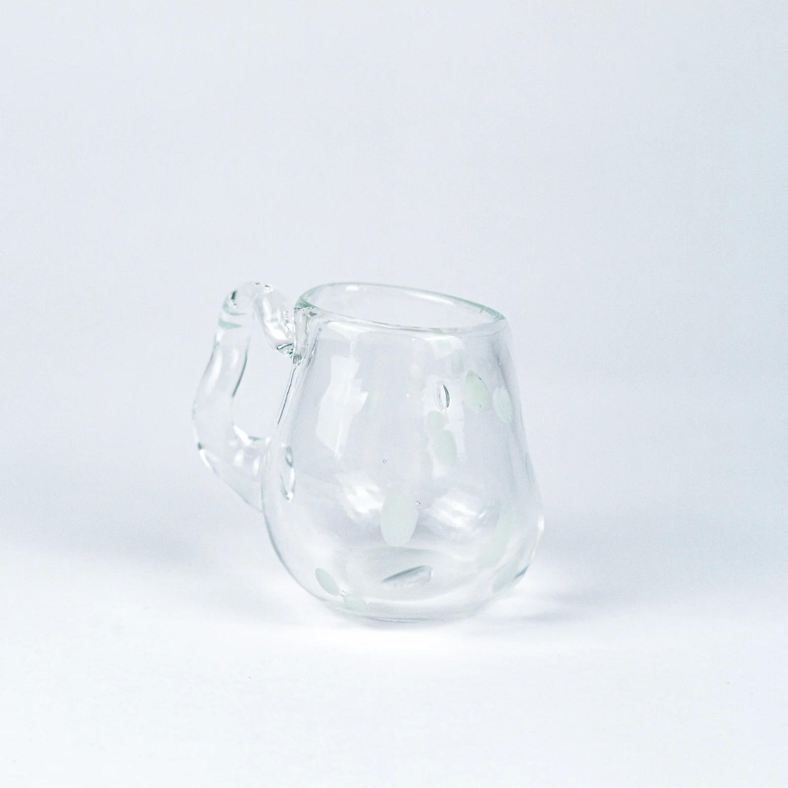 A clear glass cup with a looped handle