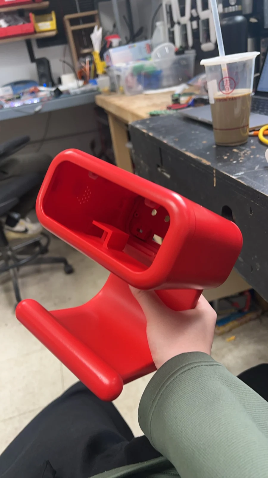 A red 3D-printed clock enclosure held before assembly