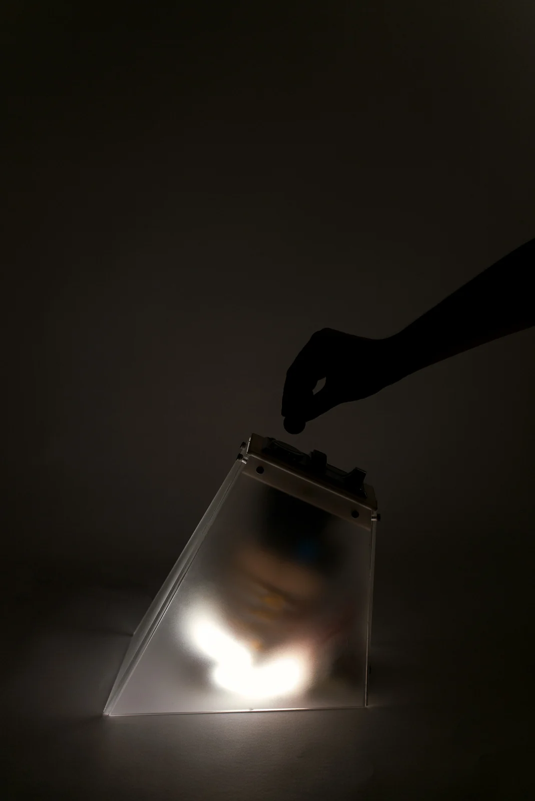 A hand inserts a coin into the glowing Quarter / Light lamp