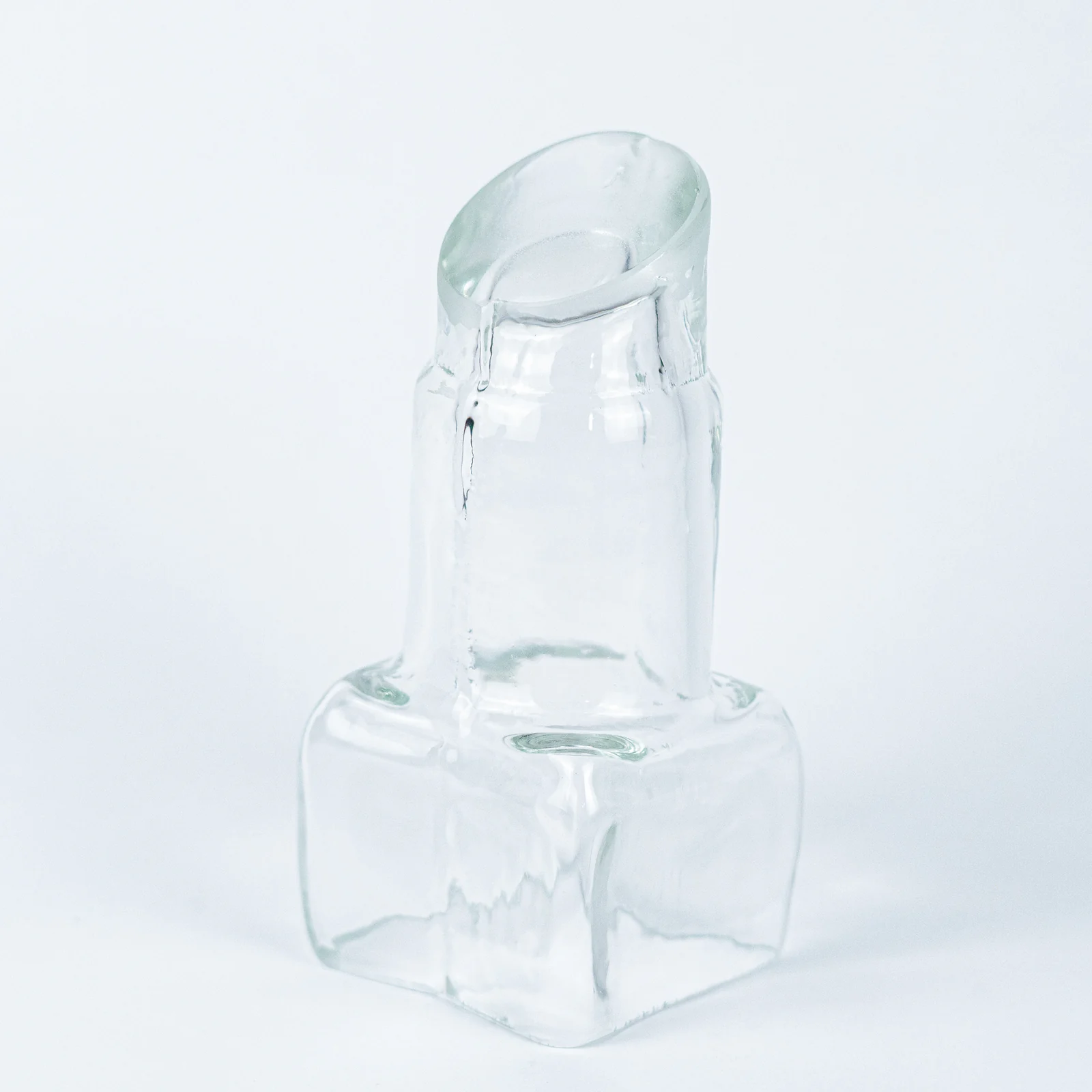 A clear glass lipstick sculpture on a square base