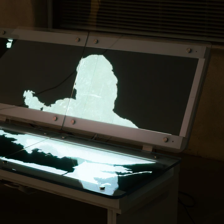 A glowing figure on a screen in a dark room