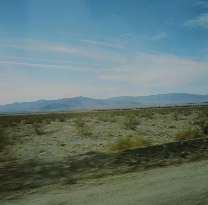 Desert scrub and distant mountains beneath a blue sky