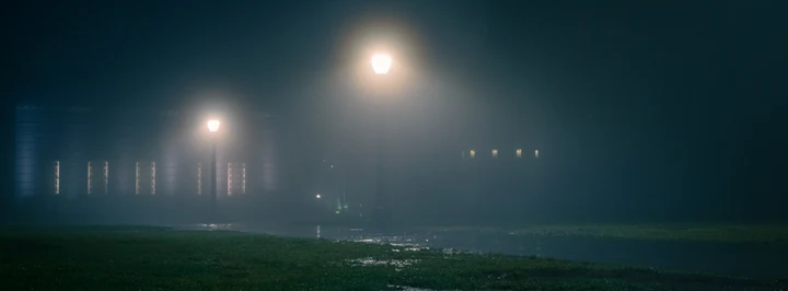 Two streetlights glowing through night fog