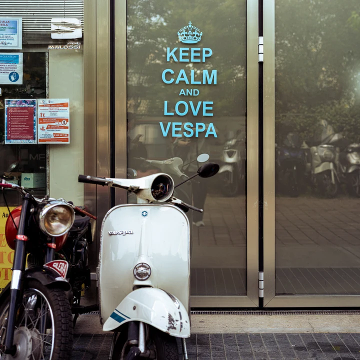 A white scooter parked outside a shop