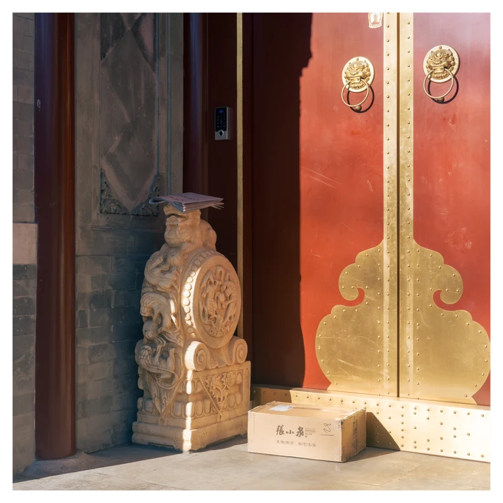 A stone figure beside red doors