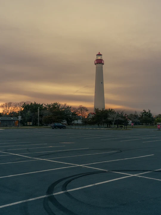 A lighthouse beyond an empty car park