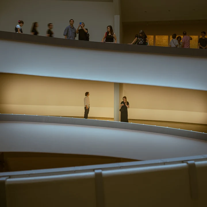 Small figures on a sloping indoor walkway