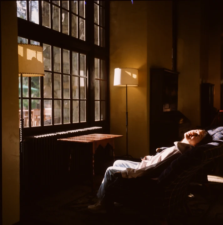 A person resting beside a warmly lit window