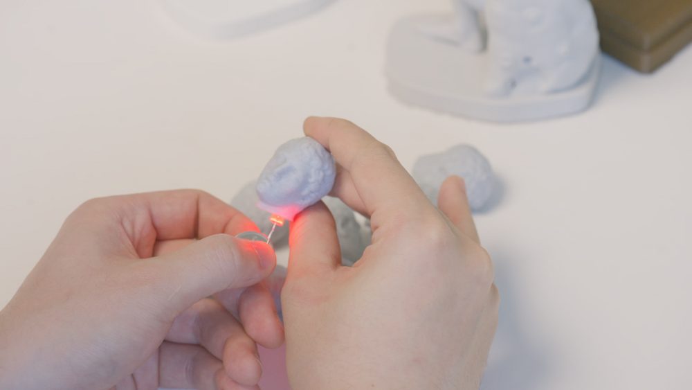 Hands working on a light sculpture